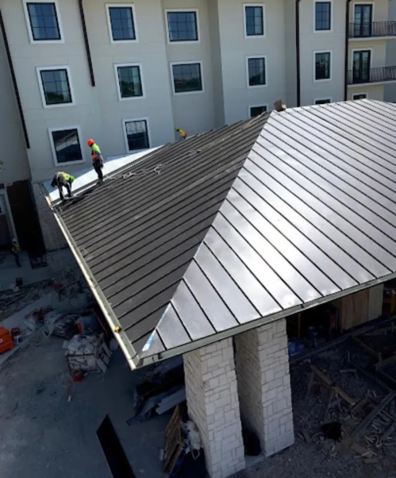 Crew installing standing seam metal roof panels on a commercial project in Lorton